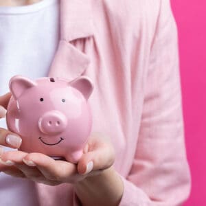 Woman's torso showing, and in her hands she is holding small pink piggy bank that is smiling. It represents birth control cost.